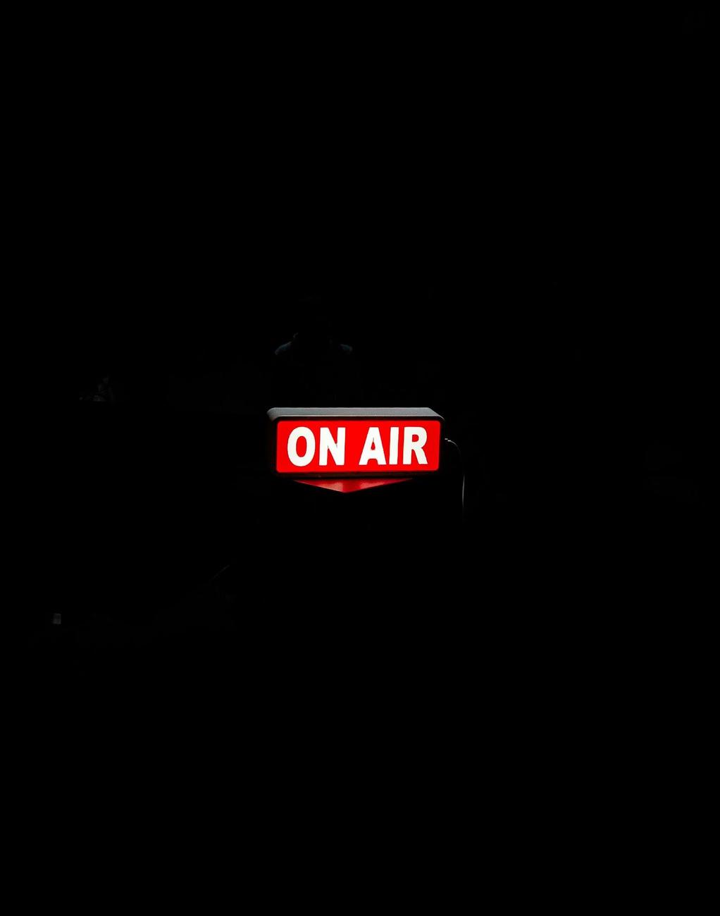 An 'on air' light glowing in a dark studio